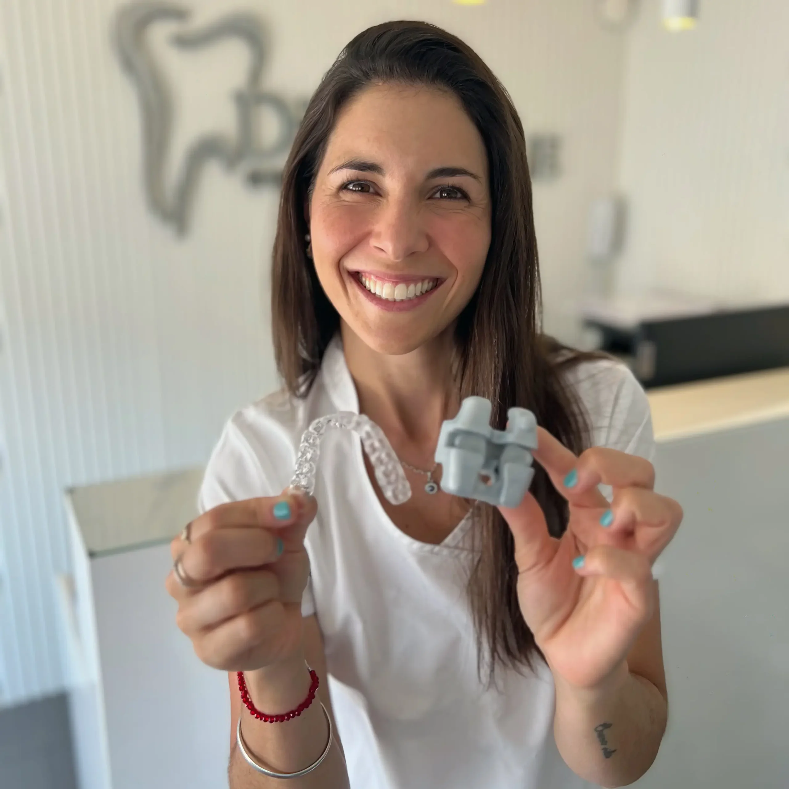 Dra. Luisina Biancalana sosteniendo alineadores y brackets en DiBian Odontología, Belgrano